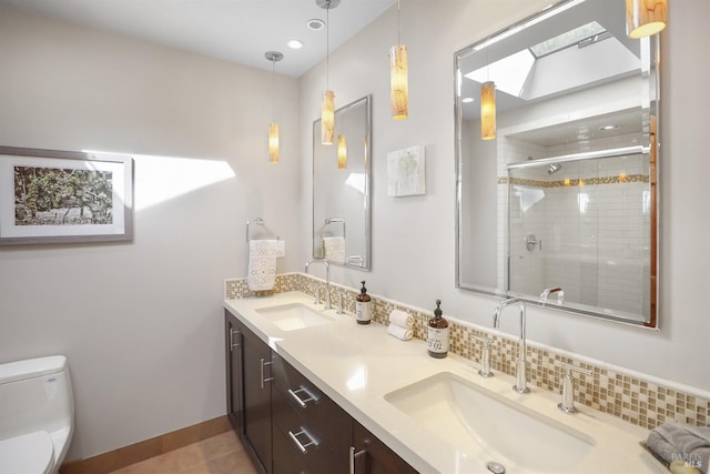 bathroom with toilet, a skylight, a shower stall, and a sink