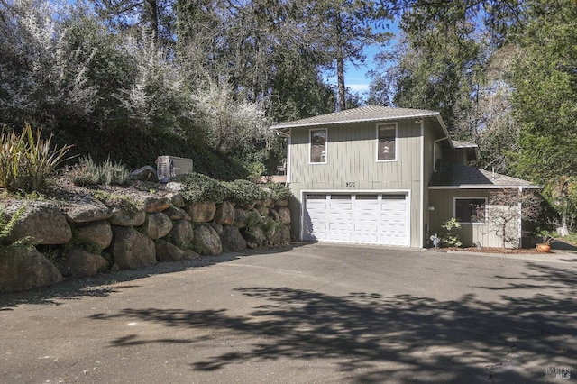 view of home's exterior with aphalt driveway, a garage, and roof with shingles