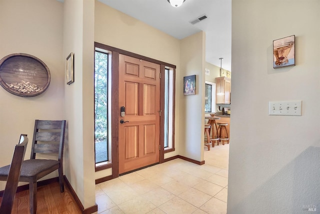 foyer entrance with baseboards and visible vents