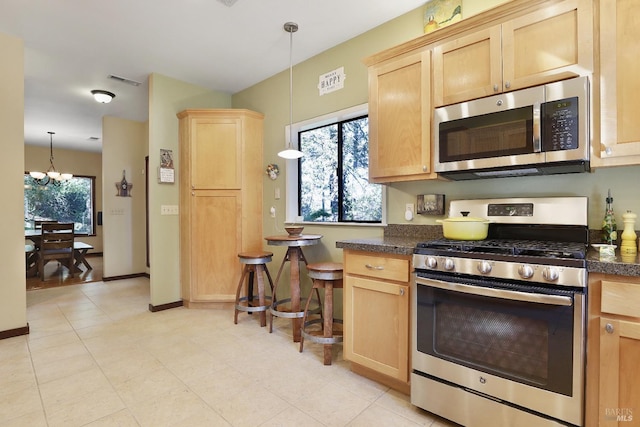 kitchen featuring dark countertops, appliances with stainless steel finishes, and light brown cabinetry