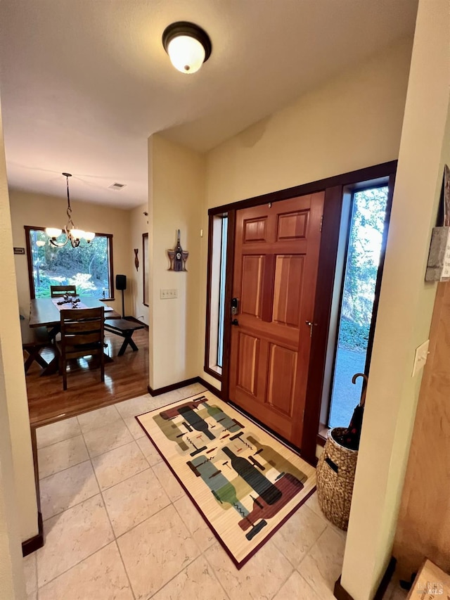 foyer featuring a chandelier, light tile patterned floors, and baseboards