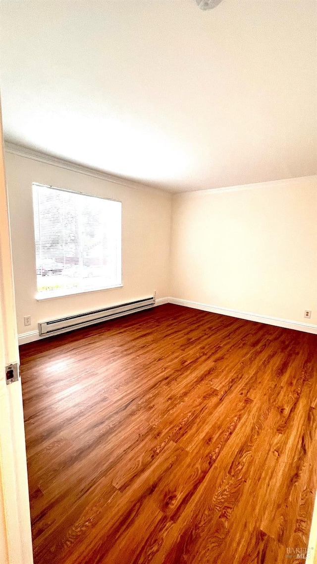 empty room with baseboards, a baseboard heating unit, and wood finished floors