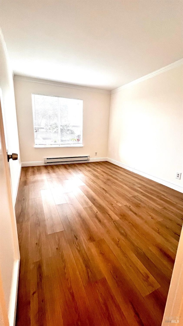 empty room featuring a baseboard radiator, baseboards, wood finished floors, and crown molding