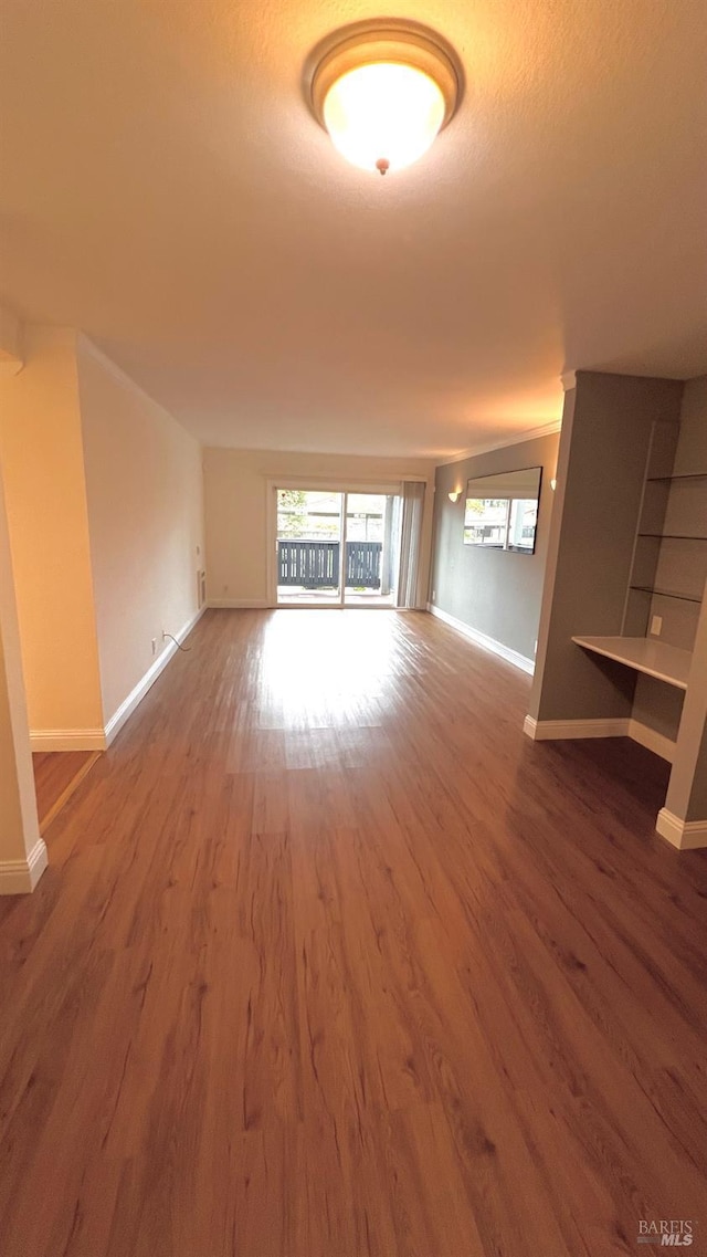 unfurnished living room with baseboards and wood finished floors