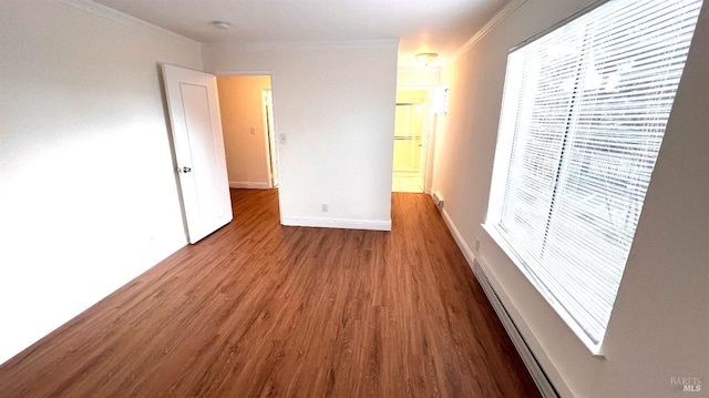 spare room featuring baseboard heating, ornamental molding, baseboards, and wood finished floors