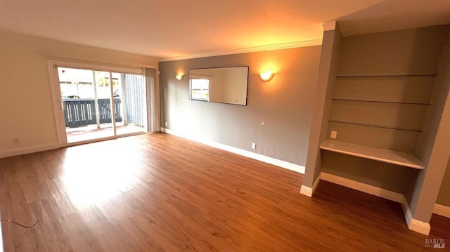 spare room with baseboards, wood finished floors, and ornamental molding