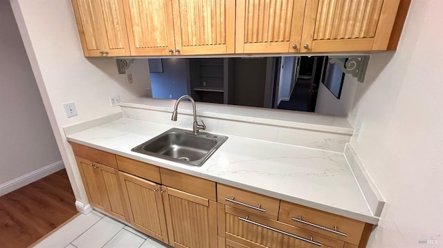 kitchen featuring a sink, baseboards, and light countertops