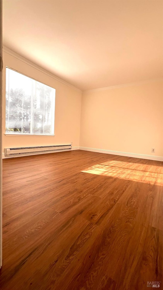 spare room with a baseboard radiator, baseboards, and wood finished floors