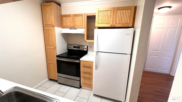 kitchen with freestanding refrigerator, ornamental molding, light countertops, under cabinet range hood, and stainless steel range with electric cooktop