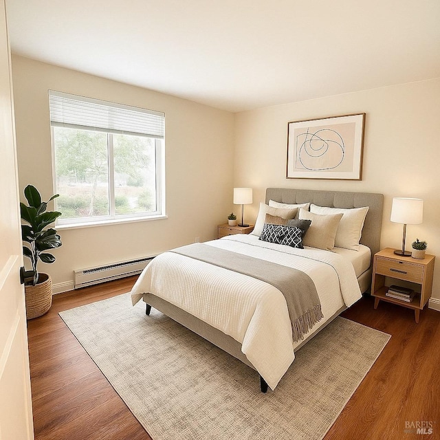 bedroom with a baseboard heating unit and dark wood finished floors