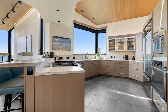 kitchen featuring light countertops, a peninsula, stainless steel appliances, glass insert cabinets, and wood ceiling