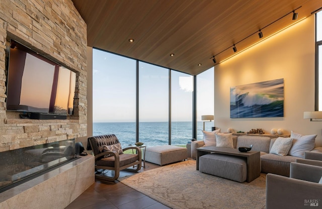 living area with rail lighting, expansive windows, dark tile patterned flooring, wood ceiling, and a fireplace