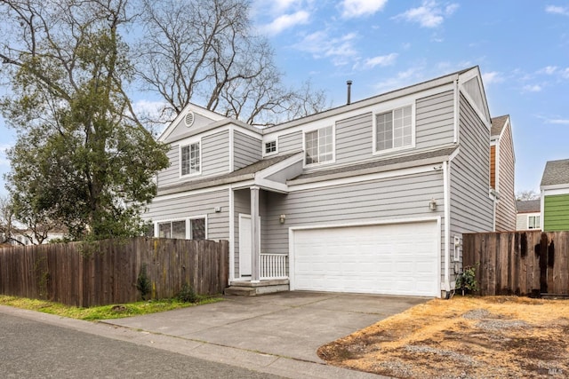 traditional-style house featuring an attached garage, driveway, and fence