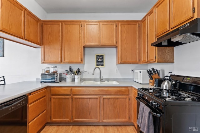 kitchen featuring under cabinet range hood, black appliances, light countertops, and a sink