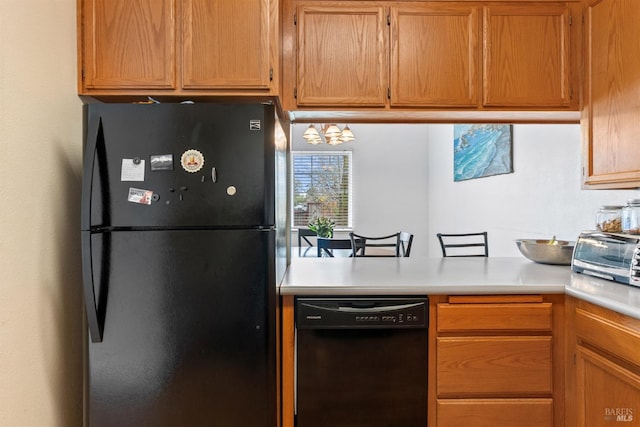 kitchen with a notable chandelier, a toaster, black appliances, and light countertops