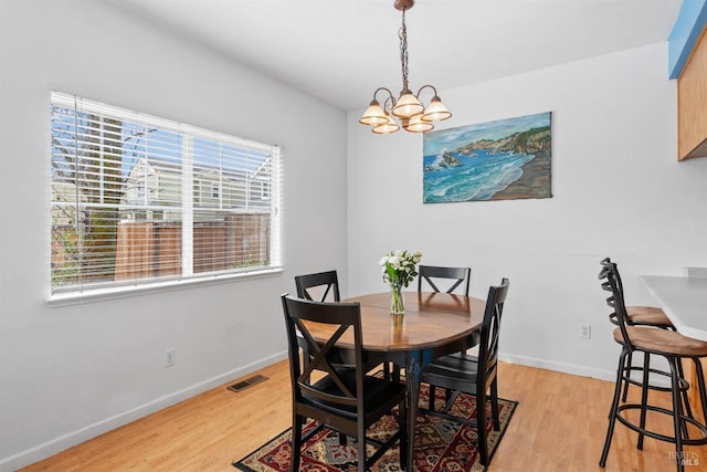 dining room with light wood-style floors, visible vents, baseboards, and a notable chandelier