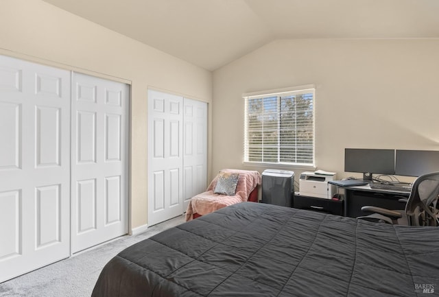 carpeted bedroom featuring lofted ceiling and two closets