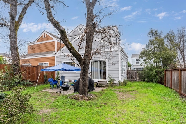 back of house featuring a fenced backyard, entry steps, a yard, and a patio