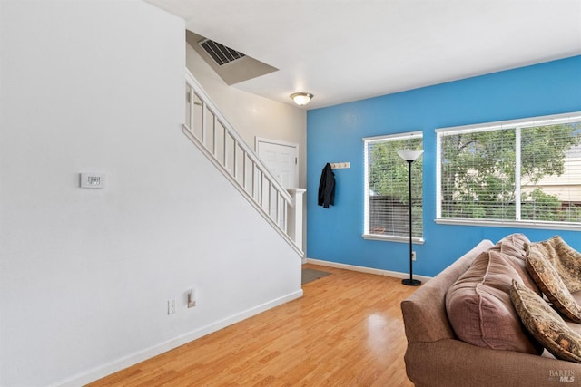 living area featuring stairway, light wood-style flooring, baseboards, and visible vents