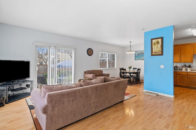 living area with a wealth of natural light, light wood-style flooring, and an inviting chandelier