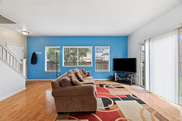 living room featuring stairs, wood finished floors, and baseboards