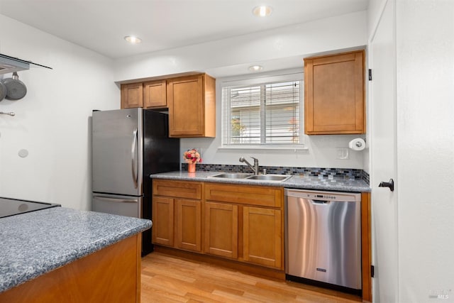 kitchen featuring light wood-type flooring, recessed lighting, brown cabinets, appliances with stainless steel finishes, and a sink