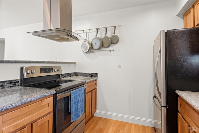 kitchen featuring light wood-type flooring, brown cabinets, stainless steel appliances, island range hood, and decorative backsplash