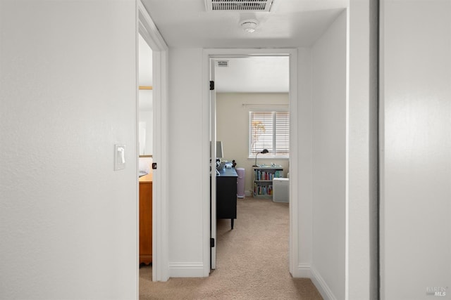 hall with visible vents, light colored carpet, and baseboards