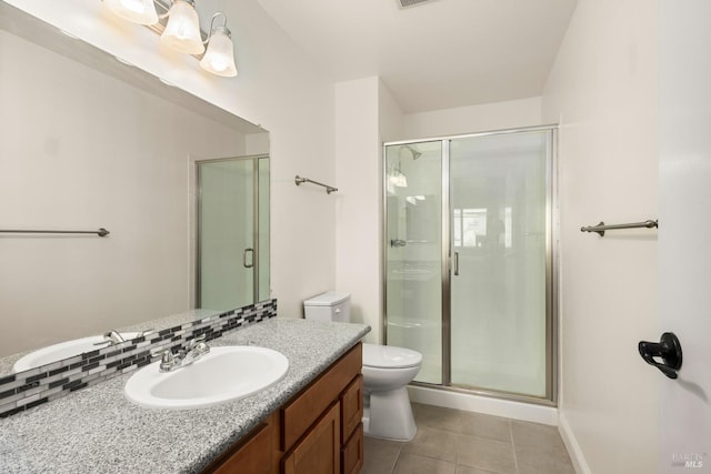 full bath with toilet, a stall shower, vanity, and tile patterned flooring