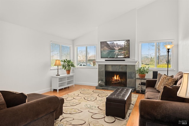 living room featuring baseboards, lofted ceiling, wood finished floors, and a tiled fireplace