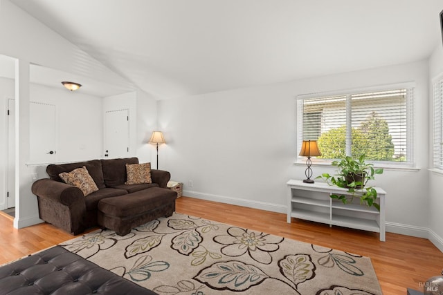 living room with lofted ceiling, light wood-style floors, and baseboards