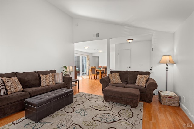 living room with vaulted ceiling, wood finished floors, visible vents, and baseboards