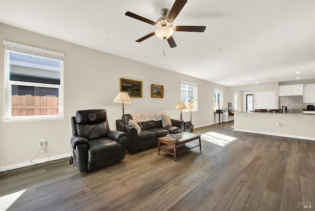 living room featuring dark wood finished floors, baseboards, and a ceiling fan