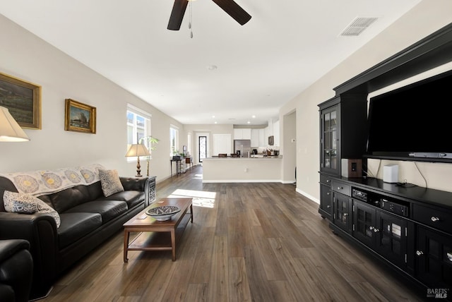 living room featuring dark wood finished floors, a ceiling fan, visible vents, and baseboards