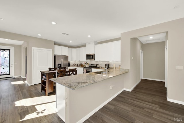 kitchen featuring visible vents, a sink, dark wood finished floors, appliances with stainless steel finishes, and a peninsula