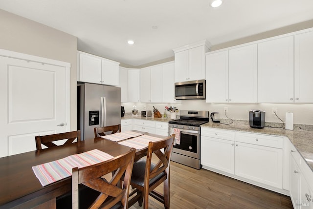 kitchen with recessed lighting, white cabinets, stainless steel appliances, and wood finished floors