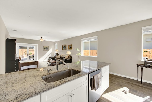 kitchen with visible vents, stainless steel dishwasher, wood finished floors, white cabinets, and a sink