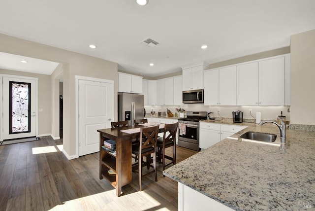 kitchen featuring a sink, stainless steel appliances, light stone counters, and visible vents