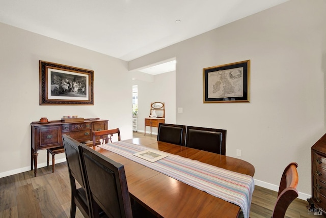 dining space with baseboards and wood finished floors