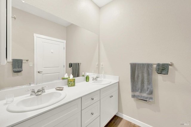 bathroom with double vanity, wood finished floors, baseboards, and a sink