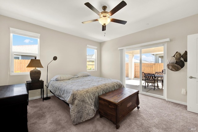 bedroom featuring multiple windows, light carpet, baseboards, and access to exterior