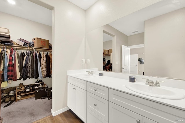 bathroom with double vanity, visible vents, a spacious closet, and a sink