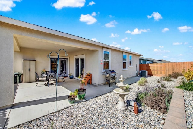 back of property featuring fence, central air condition unit, stucco siding, french doors, and a patio area