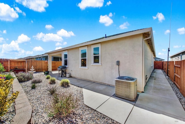 back of property with a patio, central air condition unit, a fenced backyard, and stucco siding