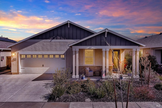 view of front of house with covered porch, stucco siding, a garage, stone siding, and driveway