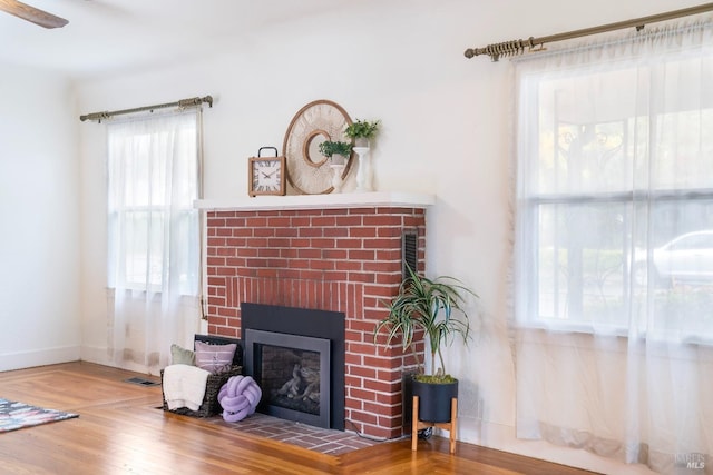 living area featuring wood finished floors, a fireplace, visible vents, and baseboards