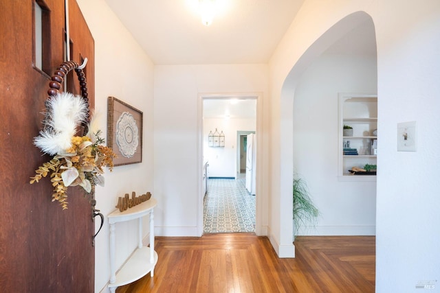 corridor featuring arched walkways, parquet flooring, and baseboards