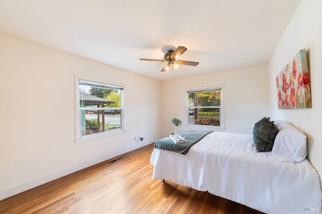 bedroom featuring visible vents, multiple windows, baseboards, and light wood-style flooring