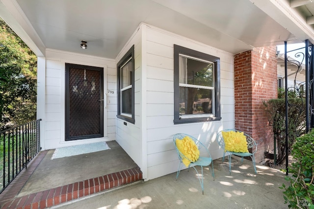 view of exterior entry with brick siding and covered porch