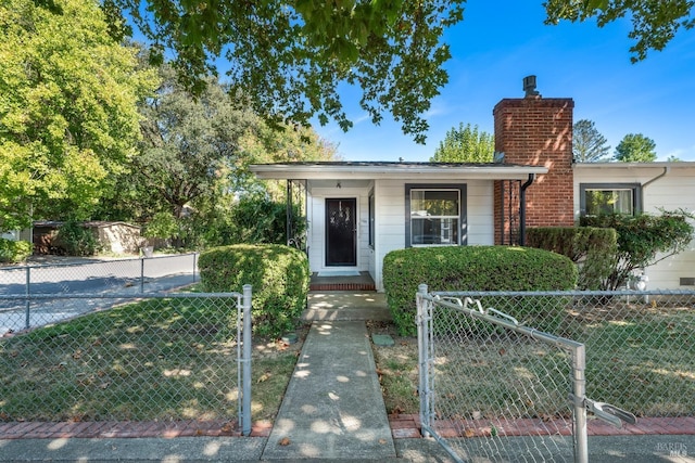 bungalow-style house with a fenced front yard, a chimney, and a gate